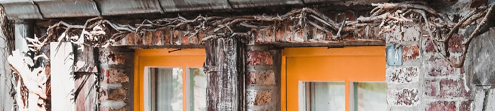 Ältere Hausfassade mit orangefarbener Tür und Fenster