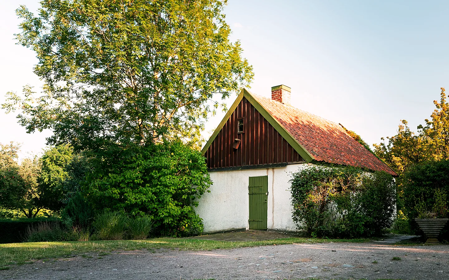 Kleines älteres Wohnhaus mit rotem Ziegeldach und Garten